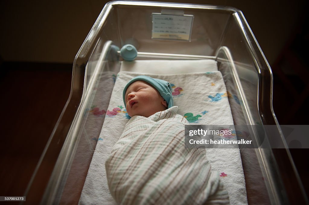 Newborn baby sleeping in hospital crib