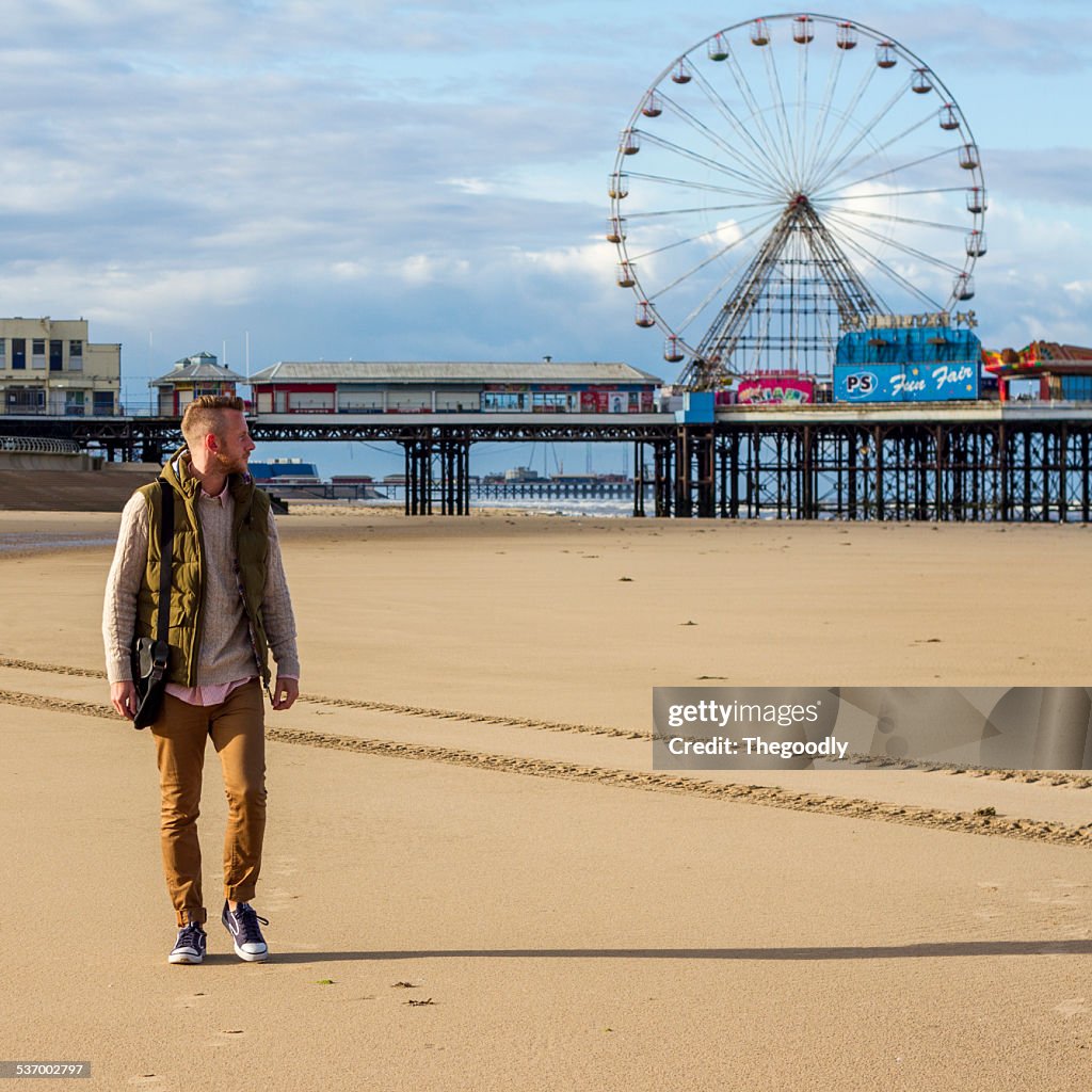 Man at beach and ferris wheel in background