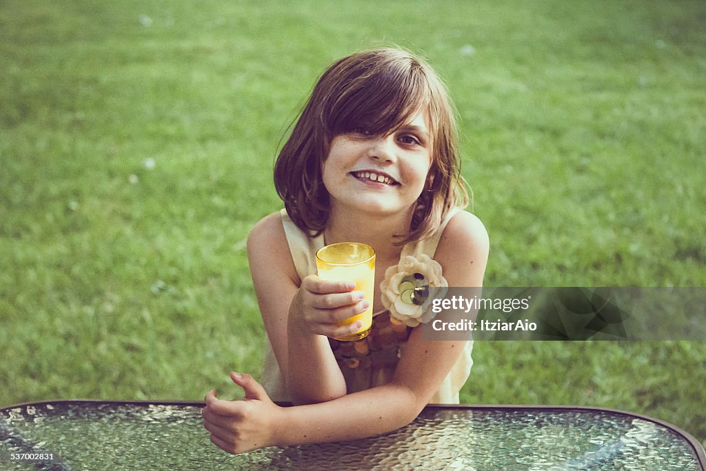 Girl with a milk moustache leaning on glass table holding glass of milk