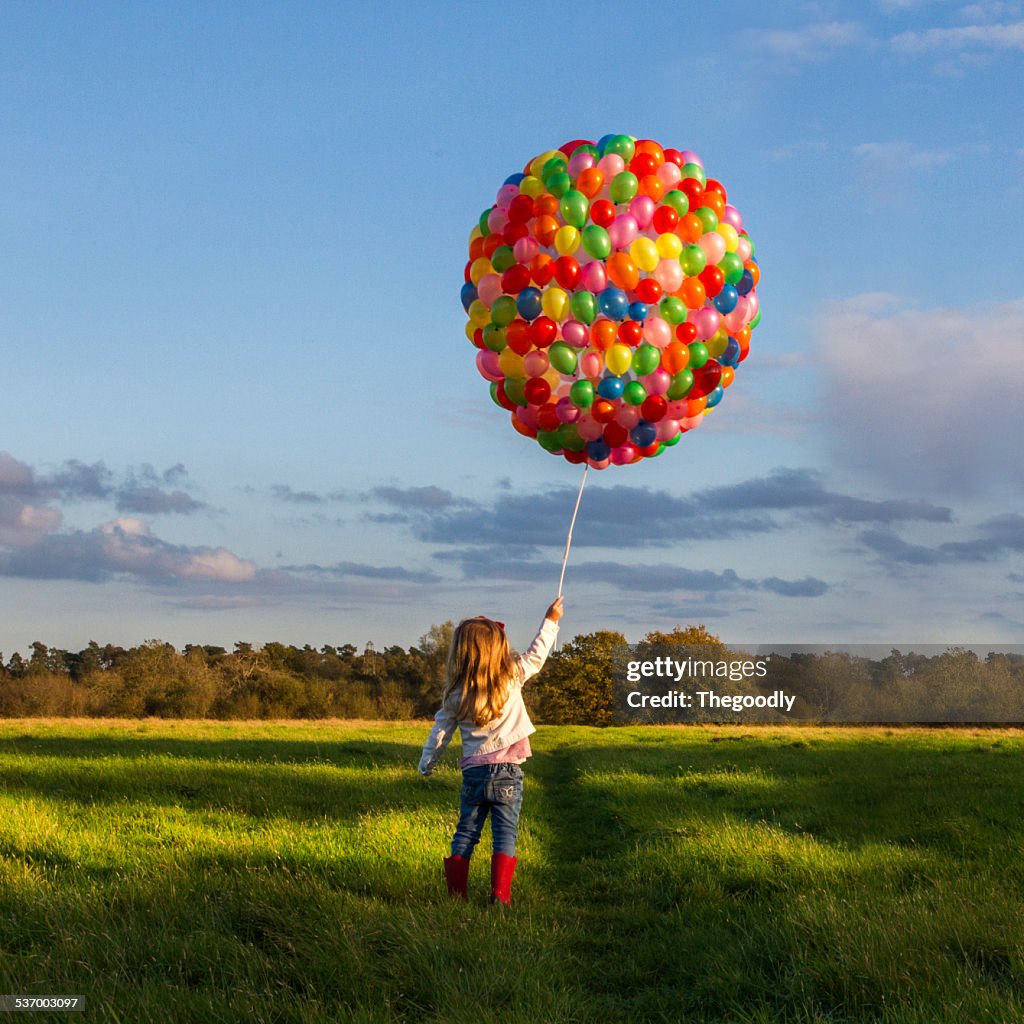 Girl with balloons in meadow