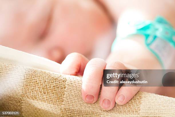 sleeping baby girl's (0-1 months) hand on cradle - hospital identification bracelet stock pictures, royalty-free photos & images