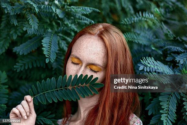 young woman with long red hair standing between trees with eyes closed - emerald green stock pictures, royalty-free photos & images