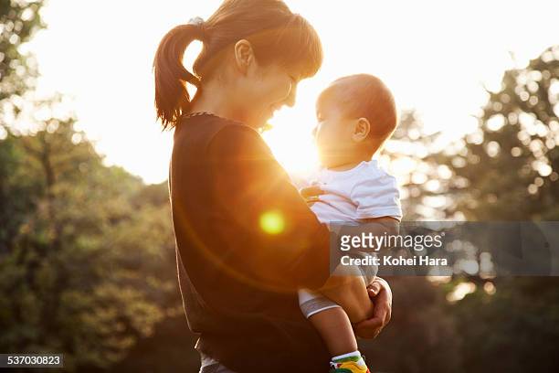 mother and baby relaxed in the park - asian family in park stock-fotos und bilder