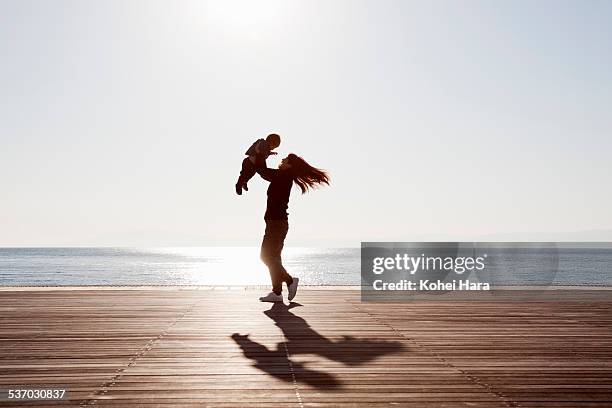 mother and baby relaxed at seaside terrace - baby light stock-fotos und bilder