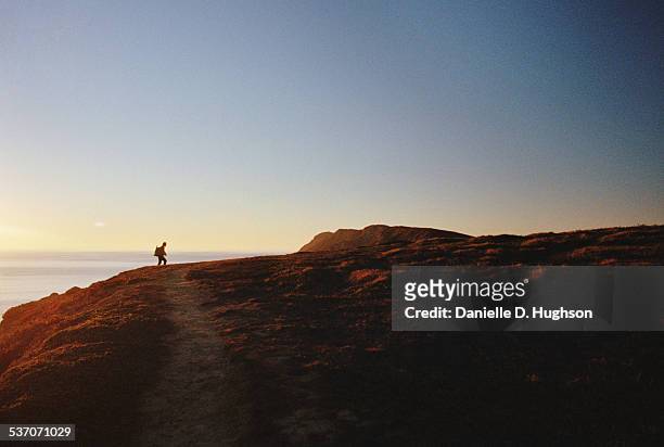 hiker climbing hill above ocean at sunset - marin county photos et images de collection