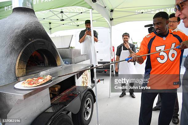 Denver Broncos player Kayvon Websterstakes out his pizza he created at the Racca's pizzeria napoletana tent during a Taste of the Broncos media...