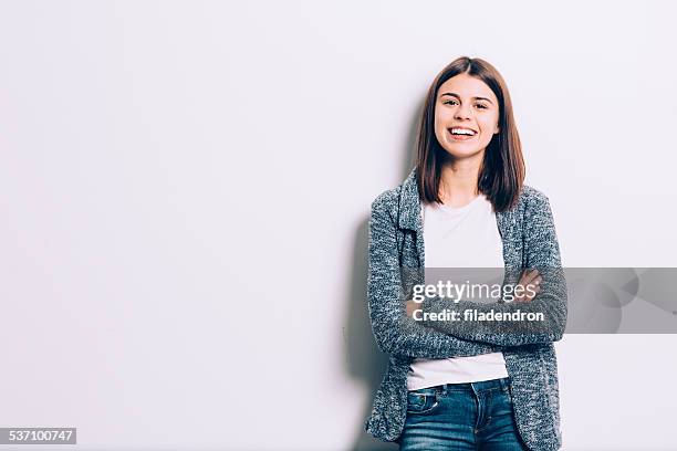 confident brunette leaning against the wall - young women white background stock pictures, royalty-free photos & images