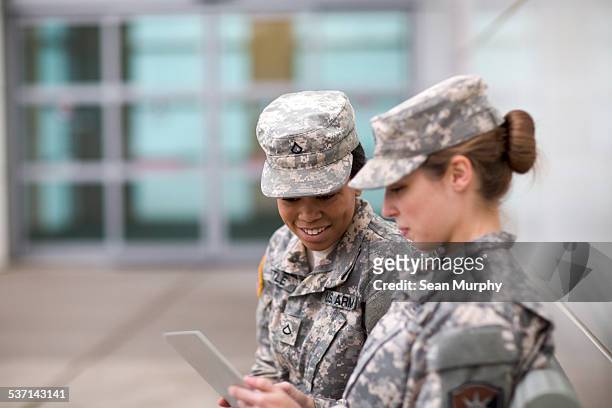 two military girls looking at tablet - armed forces stock-fotos und bilder