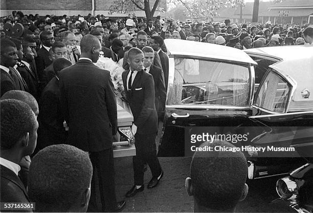 Mourners watch as group of young pallbearers carry a casket towards a hearse at a funeral for victims of the 16th Street Baptist Church bombing in...