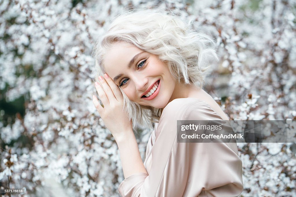 Hermosa chica en el fondo de primavera arbusto