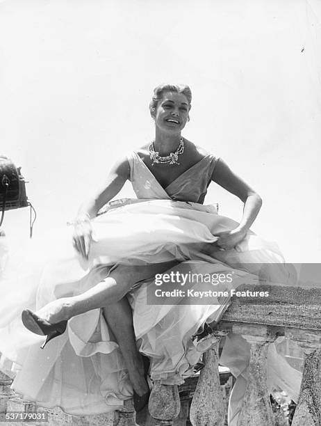 Portrait of swimmer and actress Esther Williams, sitting on a balustrade wearing a ball gown, during the filming of 'La Modella', Rome, July 15th...