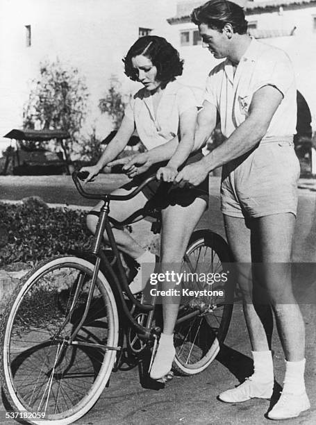 Actor Johnny Weissmuller teaching actress Lupe Velez how to ride a bicycle, December 22nd 1932.