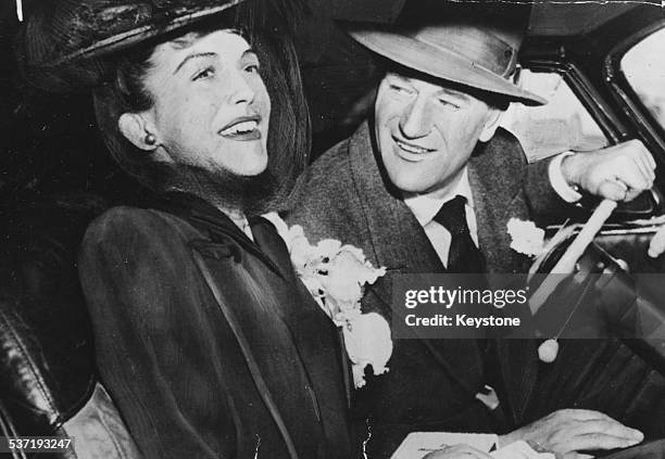 Actor John Wayne and his wife Esperanza Baur, smiling in their car following their wedding, 1945.