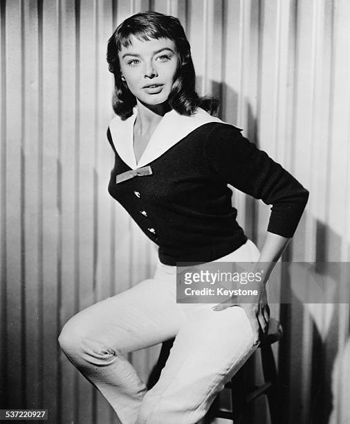 Portrait of actress Janet Munro perched on a stool, circa 1955.