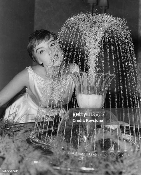 Portrait of actress Janet Munro drinking from a water fountain in the auditorium of the Astoria, at the premiere of the film 'Sleeping Beauty',...