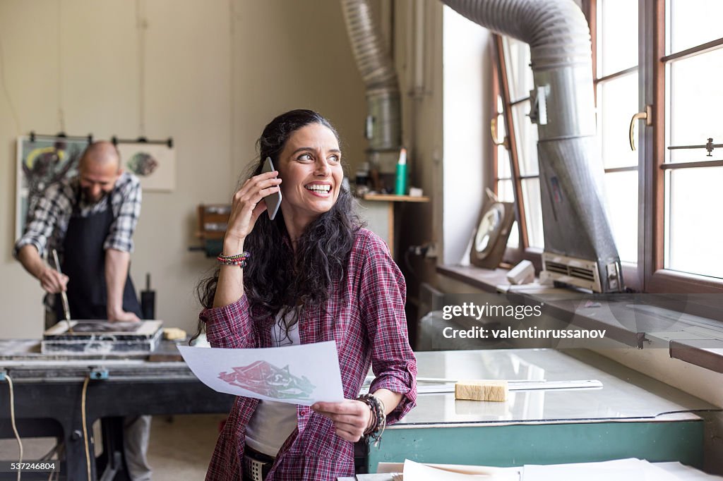 Young woman talking on the phone while printing new texture