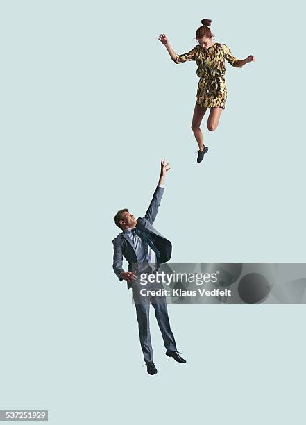 businessman reaching up in air, woman looking down - jumping imagens e fotografias de stock