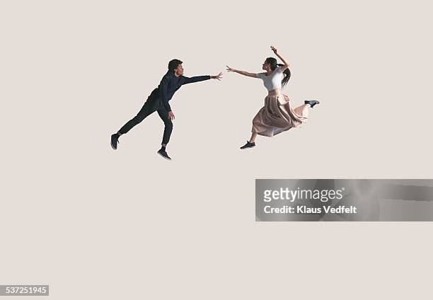 young couple in air reaching out for each othe - arms outstretched full body stock pictures, royalty-free photos & images