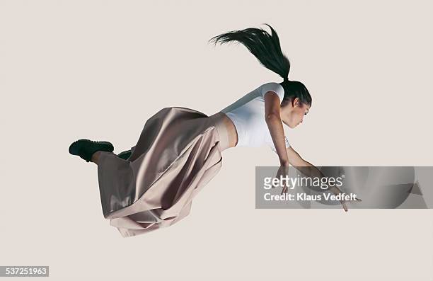 young woman in the air strecthing arm to reach out - person jumping stock-fotos und bilder