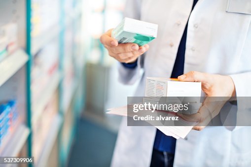 Farmacêutico as mãos a tomar medicamentos de prateleira Farmacêutico as mãos a tomar medicamentos de prateleira