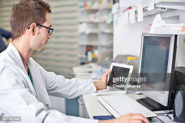 male pharmacist working at his desk - hospital pharmacy stock pictures, royalty-free photos & images
