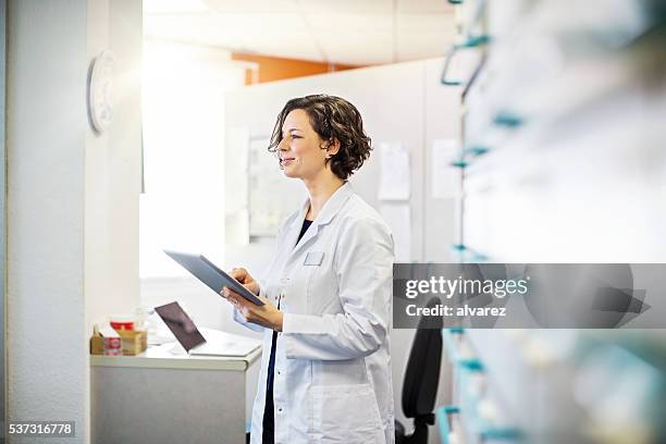 female pharmacist with a digital tablet - pharmacist stock pictures, royalty-free photos & images