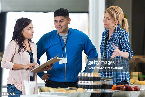 man and women overlooking food table - employee welfare stockfoto's en -beelden