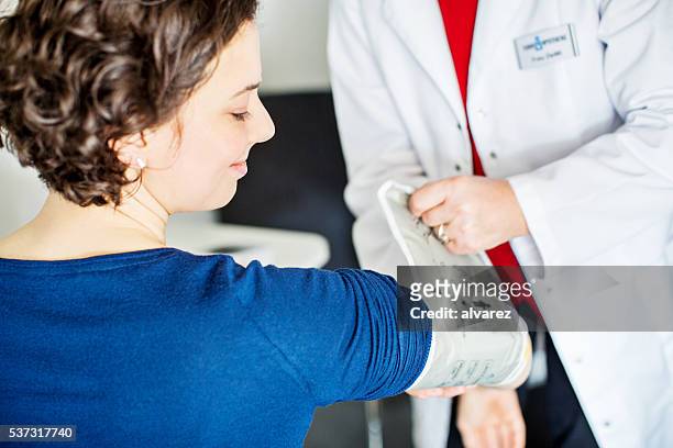 krankenschwester überprüfung blutdruck von junge frau - measure stock-fotos und bilder