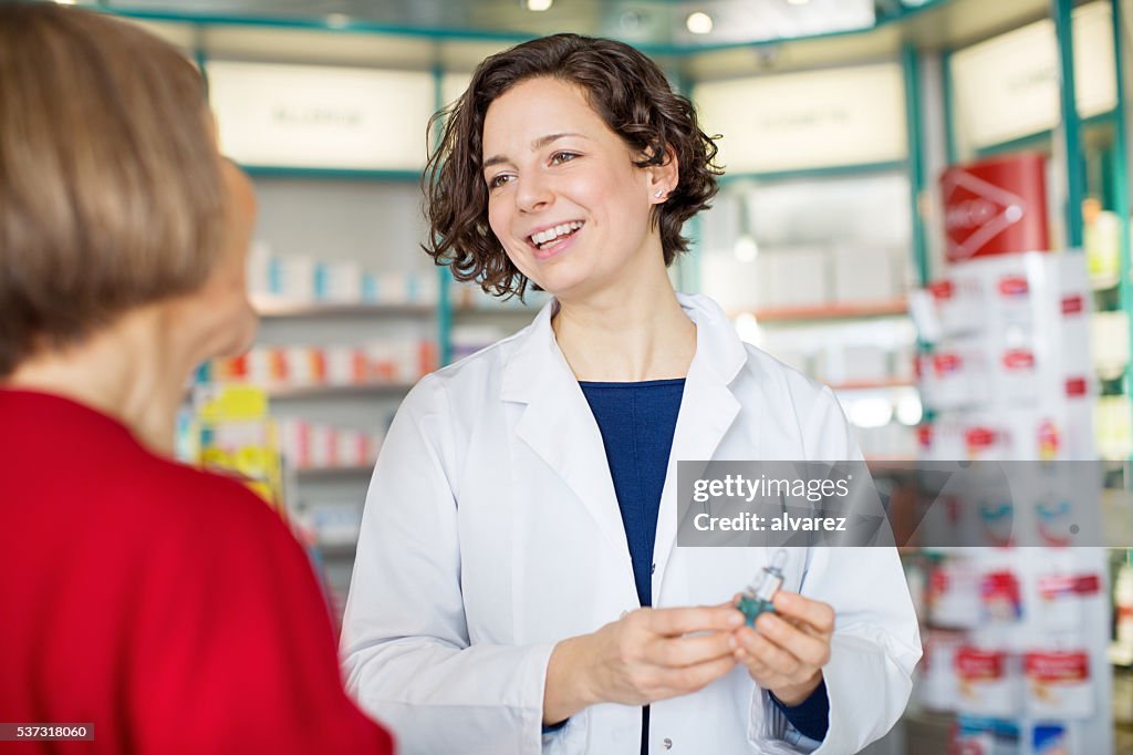 Young female pharmacist assisting customer