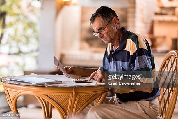 serious senior man calculating home finances on the terrace. - filing documents stock pictures, royalty-free photos & images