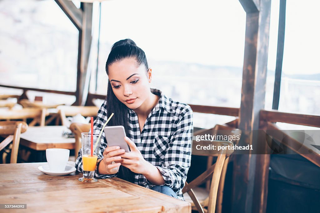 Jeune femme regardant son téléphone au Café boutique