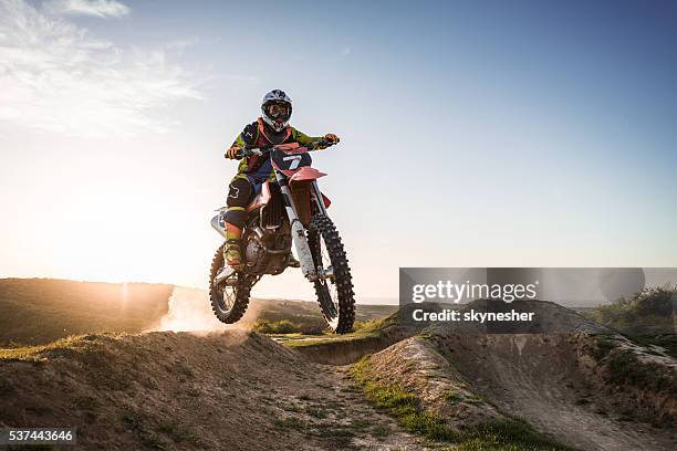 extrême pilote d'équitation de vélo de route de la terre au coucher de soleil. - motocross stock photos et images de collection