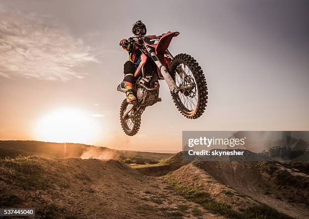 motocross sujo desempenho salto alto ao pôr-do-sol. - motociclista - fotografias e filmes do acervo