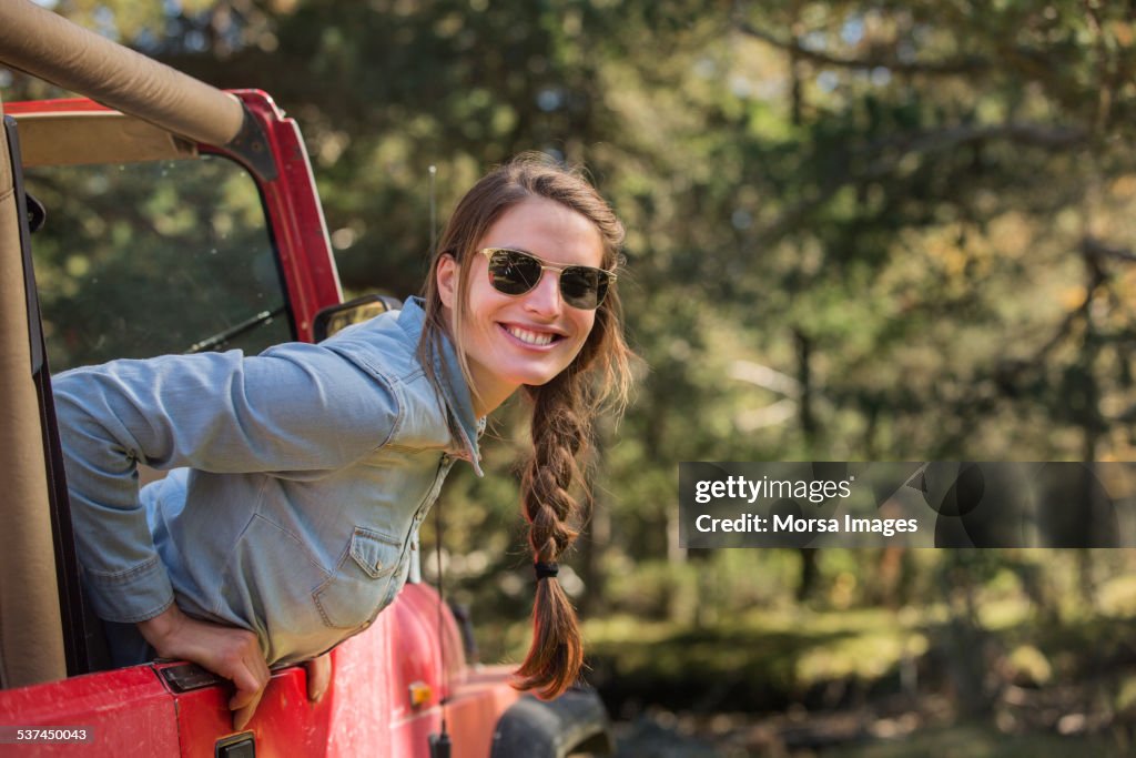 Smiling young woman leaning out of jeep