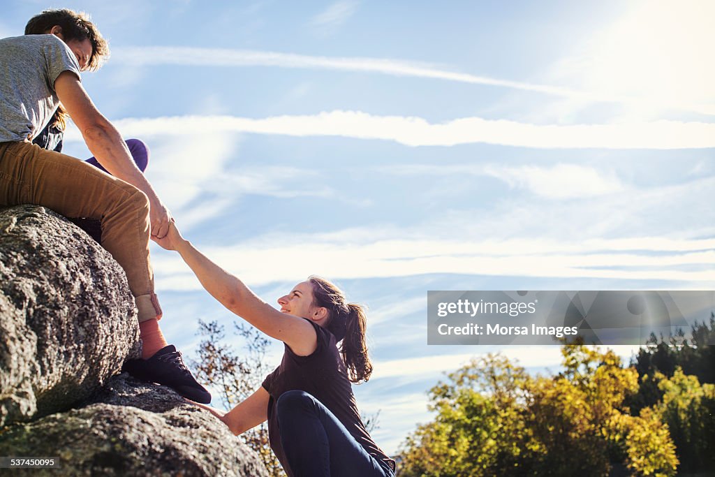 Man helping female friend to climb rock