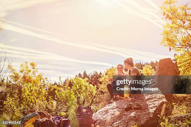 hiking female friends having snacks on rock - picnic friends ストックフォトと画像