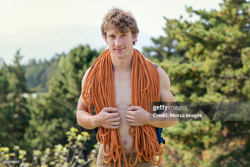 Confident male rock climber with rope around neck