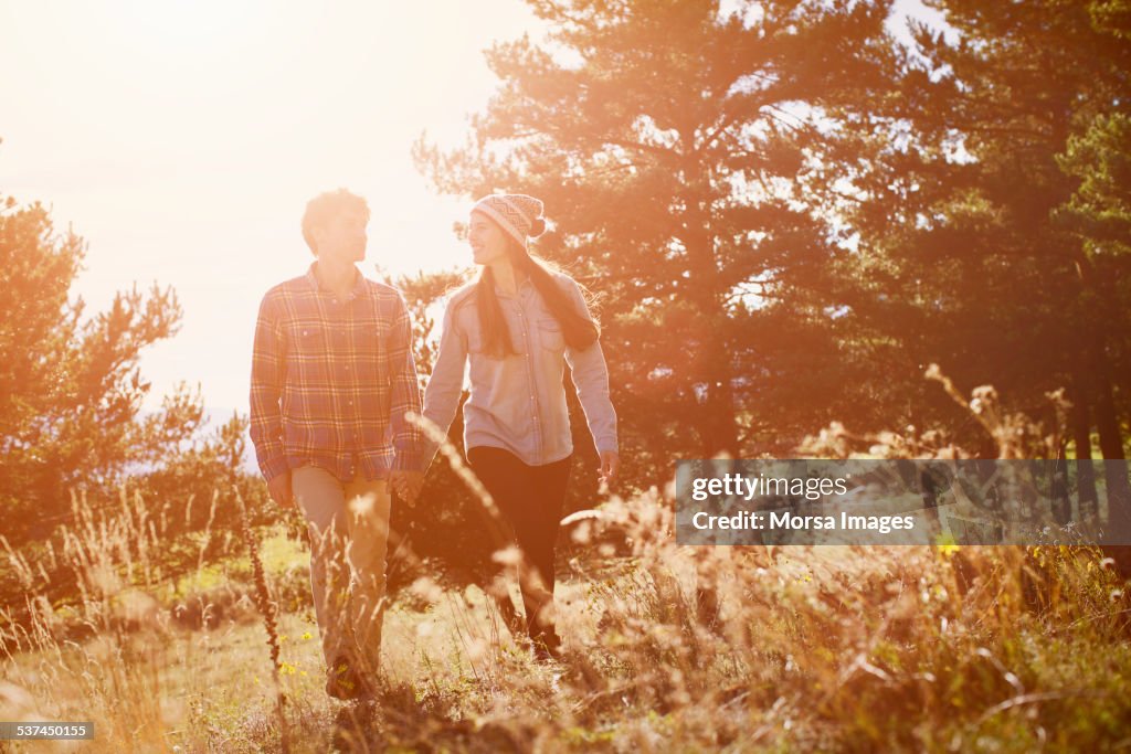 Couple holding hands while walking on field