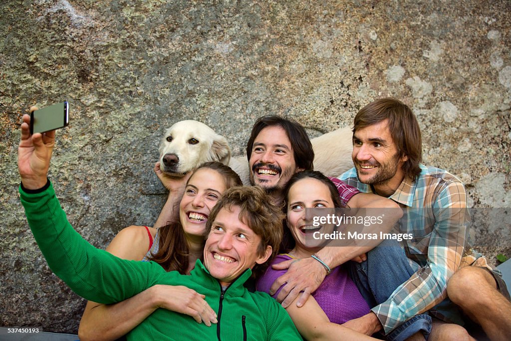 Friends taking selfie with dog against rock