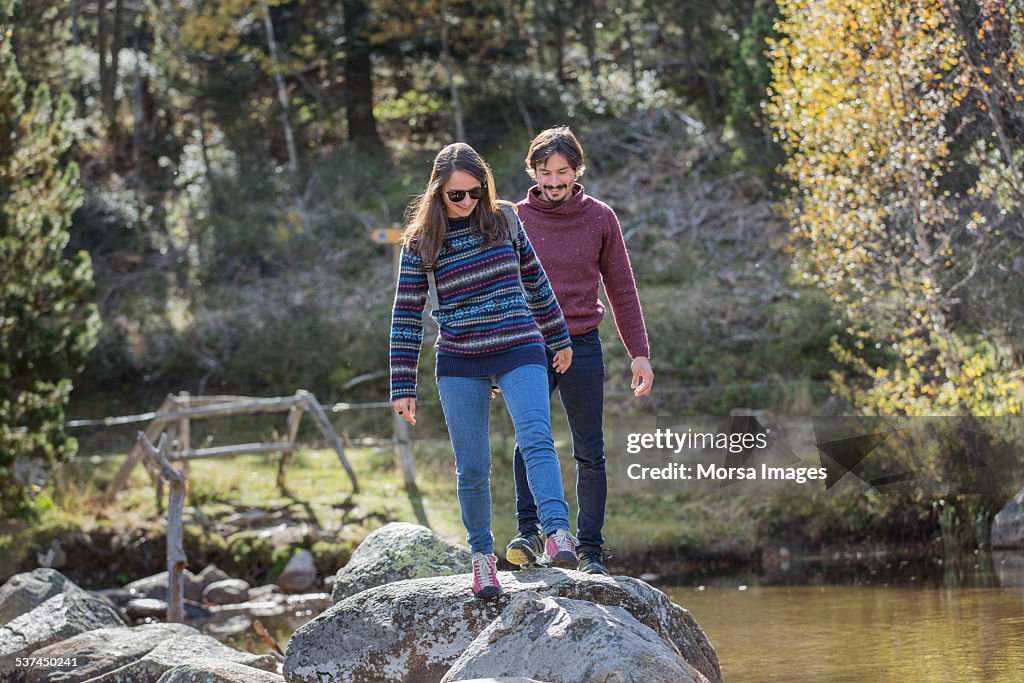 Couple crossing river in forest