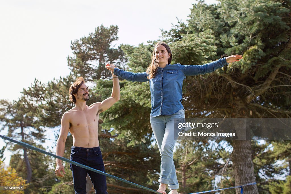 Man assisting woman to walk on slack-line