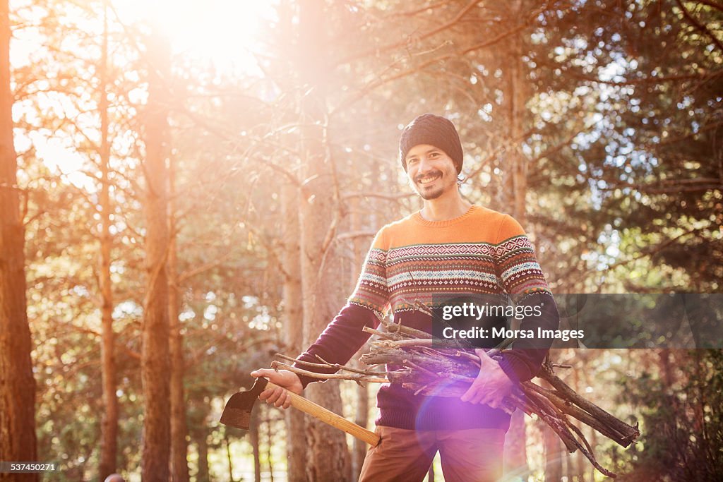 Man with axe and firewood in forest