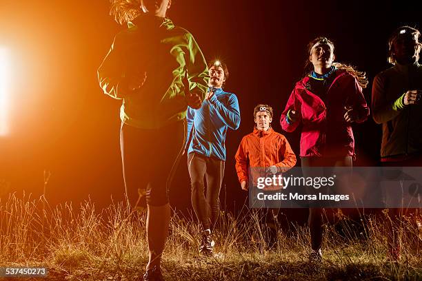 Joggers running on field at night