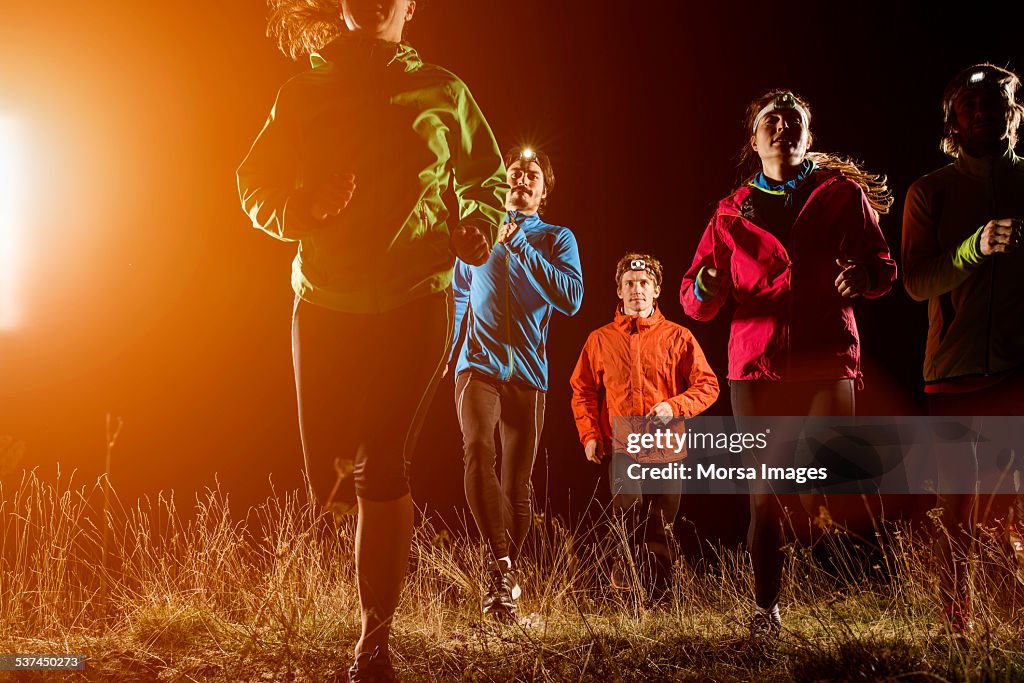 Joggers running on field at night