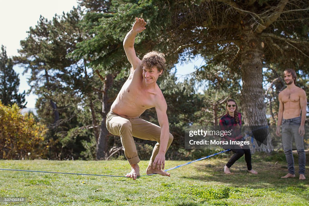 Friends watching man balancing on slack-line