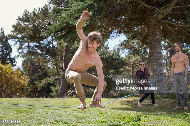 friends watching man balancing on slack-line - slackline stockfoto's en -beelden