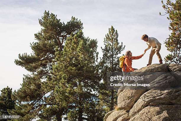 man helping friend to climb rock - escala fotografías e imágenes de stock