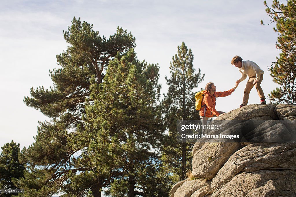 Man helping friend to climb rock