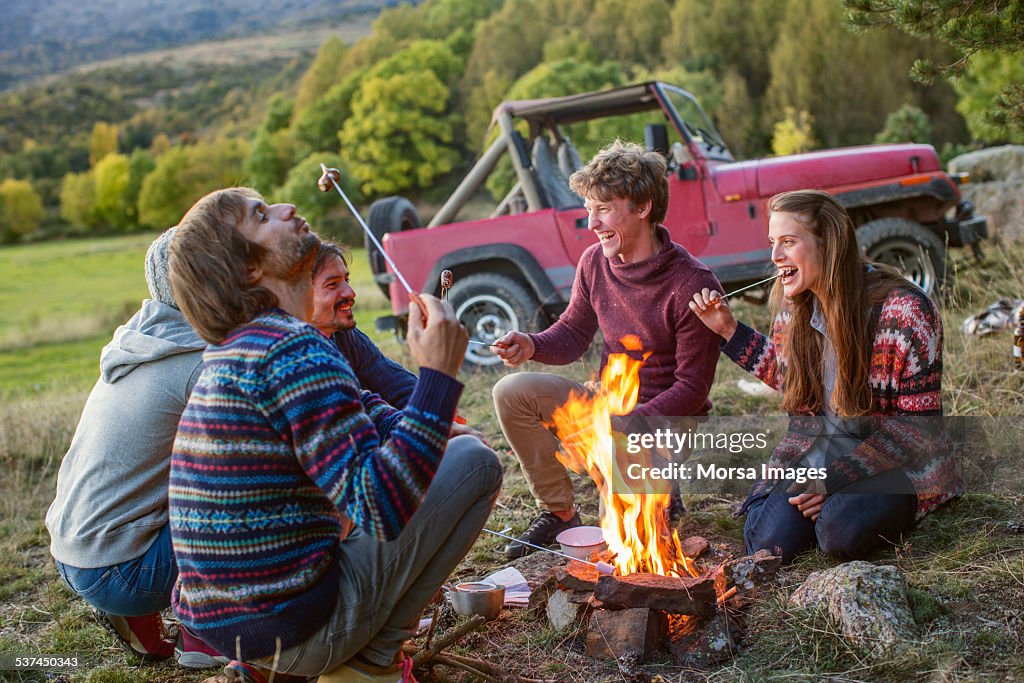 Friends eating roasted marshmallows at campsite