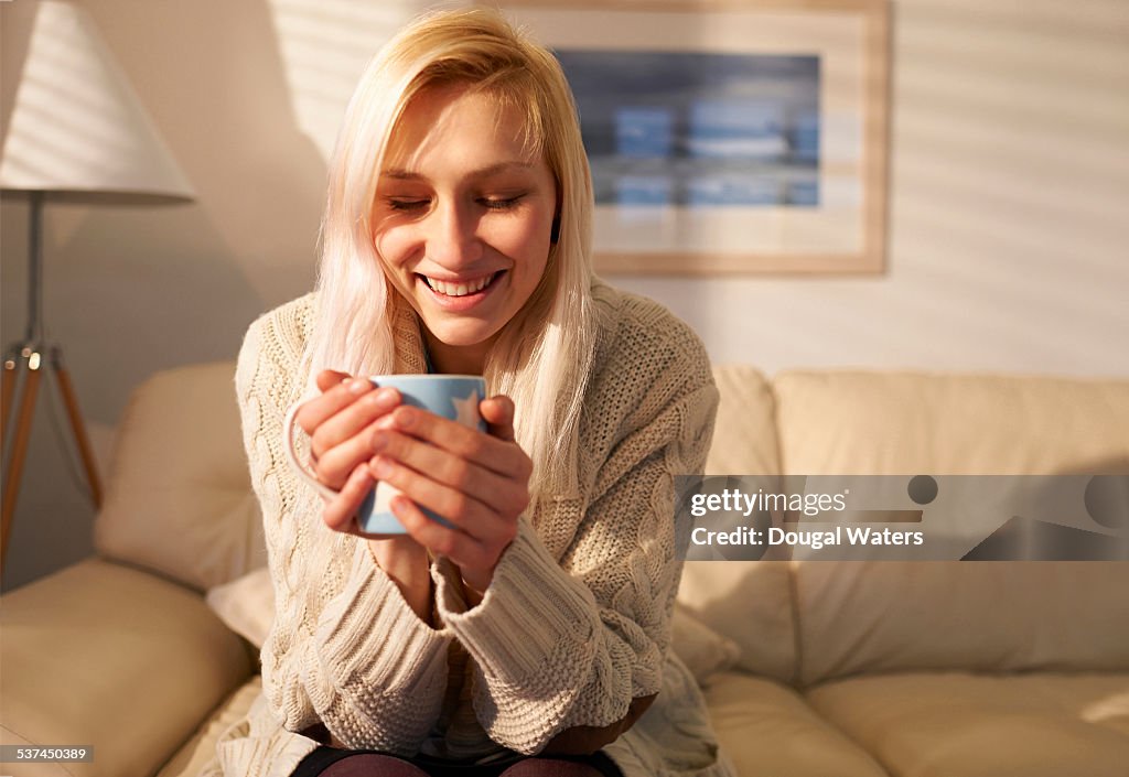 Woman relaxing at home with hot drink.